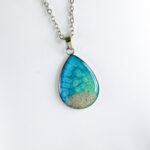 Soča ogrlica v obliki kapljice, modro-zelena s pravim peskom iz reke Soče, ročno izdelana iz nerjavečega jekla.