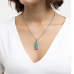 Ročno izdelana ogrlica pravokotne oblike z modro-zeleno poslikavo in pravim peskom iz reke Soče, unikatni kos nakita iz Slovenije, prikaz na modelu