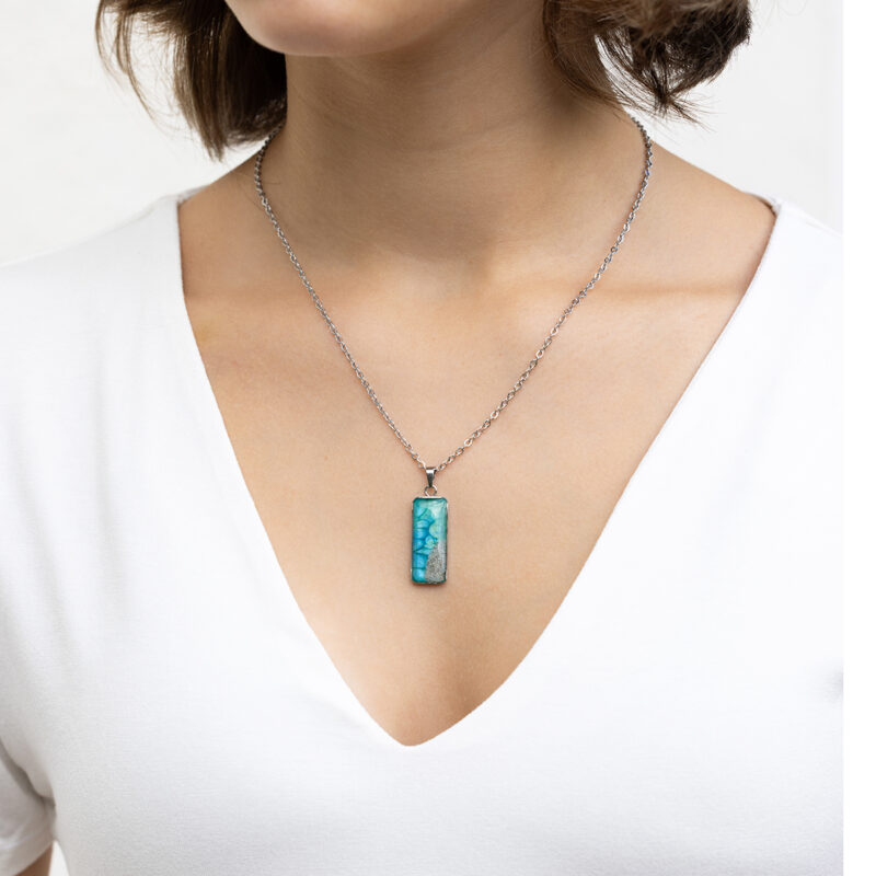 Ročno izdelana ogrlica pravokotne oblike z modro-zeleno poslikavo in pravim peskom iz reke Soče, unikatni kos nakita iz Slovenije, prikaz na modelu