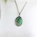 Ogrlica z ovalnim zelenim medaljonom, peskom iz reke Soče in sijočo smolo – ročno izdelano darilo za ljubiteljice narave.