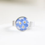 Ročno izdelan prstan iz nerjavečega jekla s pravimi posušenimi spominčicami in prozorno smolo – minimalističen kos z naravnim pridihom.