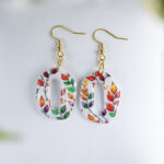 Viseči jesenski uhani z motivom pisanih listkov v rumeni, oranžni, rdeči in zeleni barvi, izdelani iz polimerne gline in prevlečeni z umetno smolo.