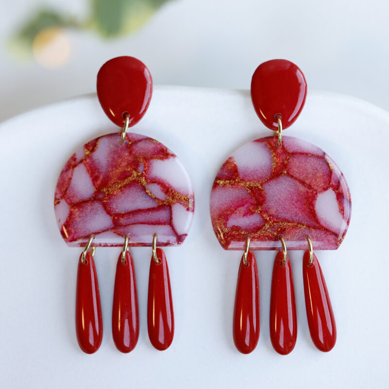 Rdeči viseči uhani z zlatimi poudarki, ročno izdelani iz polimerne gline in preliti z umetno smolo.