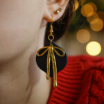 Viseči črni uhani z zlato mašnico prikaz na ušesu