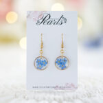 Ročno izdelani viseči uhani z modrimi spominčicami v zlati okrogli osnovi iz medenine in nerjavečega jekla