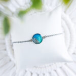 Zapestnica Soča z okroglim medaljonom v modro-zelenih tonih in pravim peskom iz reke Soče, premera 17 mm.