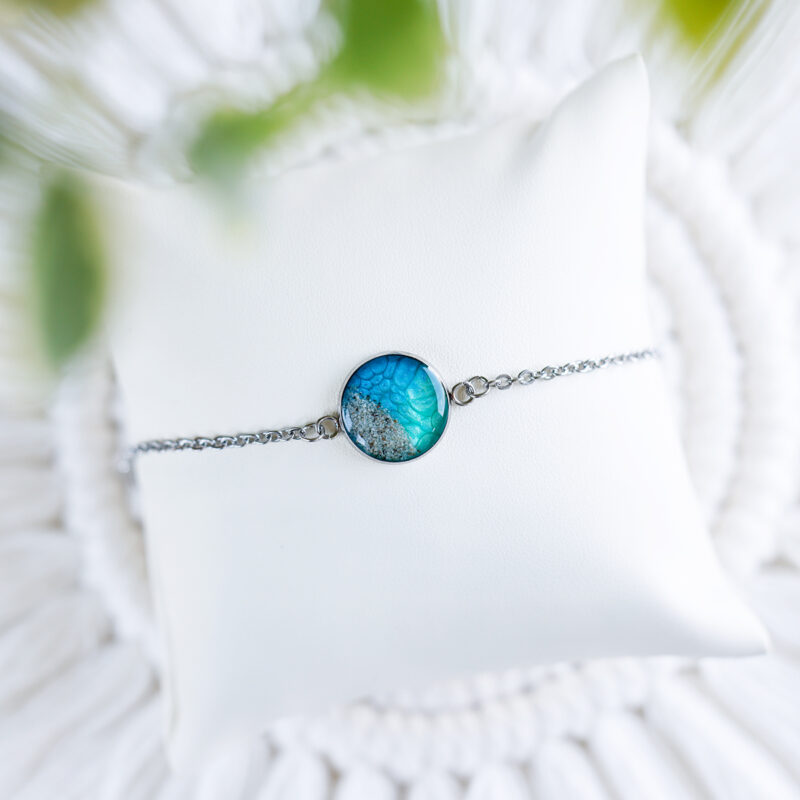 Zapestnica Soča z okroglim medaljonom v modro-zelenih tonih in pravim peskom iz reke Soče, premera 17 mm.