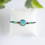 Zapestnica z okroglim zeleno-modrim delom velikosti S, premer 1,4 cm, in peskom iz reke Soče